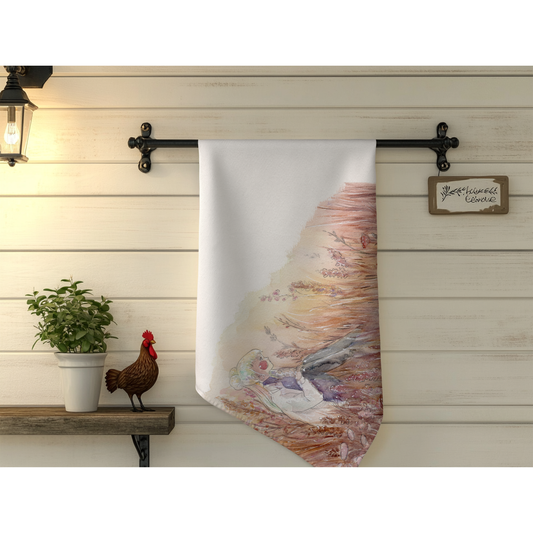 Decorative towel with artistic design hanging on a wooden wall with a plant and rooster.
